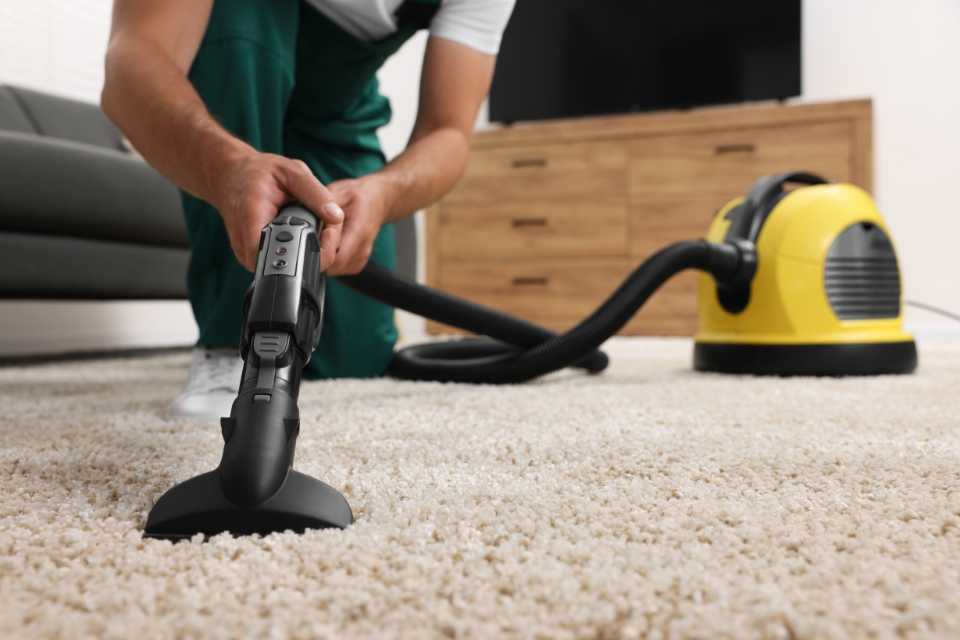 person vacuuming new white carpet in living room